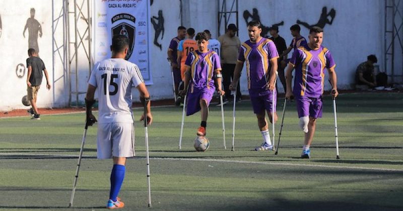 شباب فلسطينيون من مبتوري الأطراف يلعبون كرة القدم على ملعب متضرر في مدينة غزة