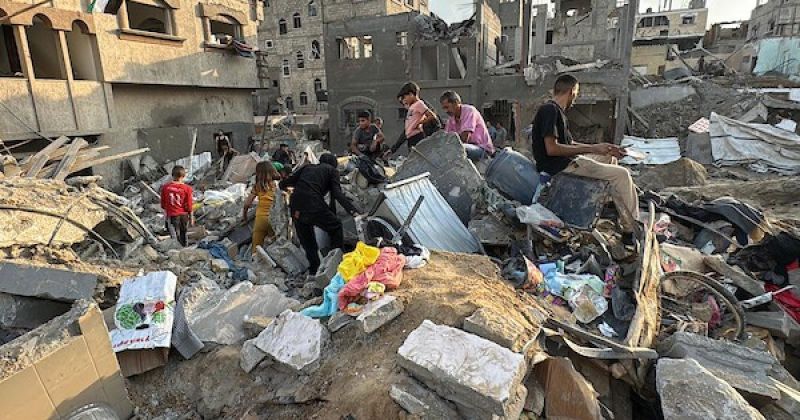 فلسطينيون يتفقدون المباني المدمرة في موقع غارة جوية إسرائيلية على مخيم المغازي