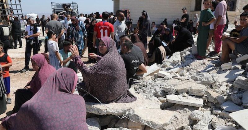 فلسطينيون على أنقاض منزل هدمته القوات الإسرائيلية في بلدة بيت عوا