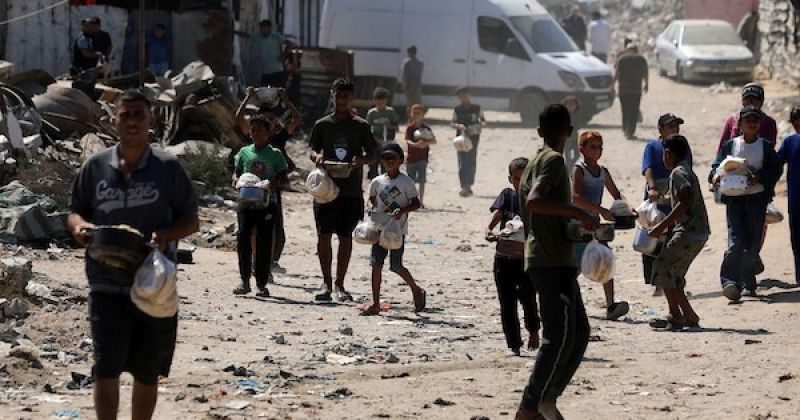 تجمع نازحون بينهم نساء وأطفال لتلقي وجبات طعام من مركز توزيع خيري شرق غزة