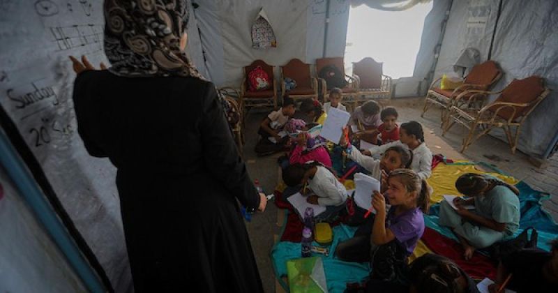 أطفال فلسطينيون يحضرون درساً داخل خيمة تعليمية مؤقتة